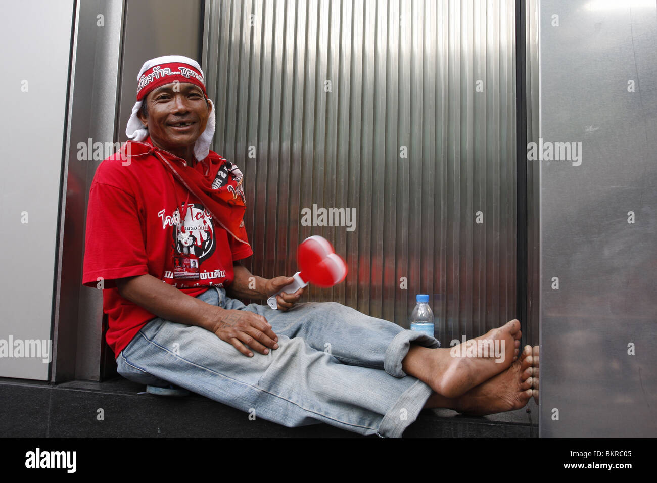 Un chandail rouge manifestant campagne pour le retour des disgraciés PM Thaksin Shinawatra, prend un repos dans le centre de Bangkok. Banque D'Images