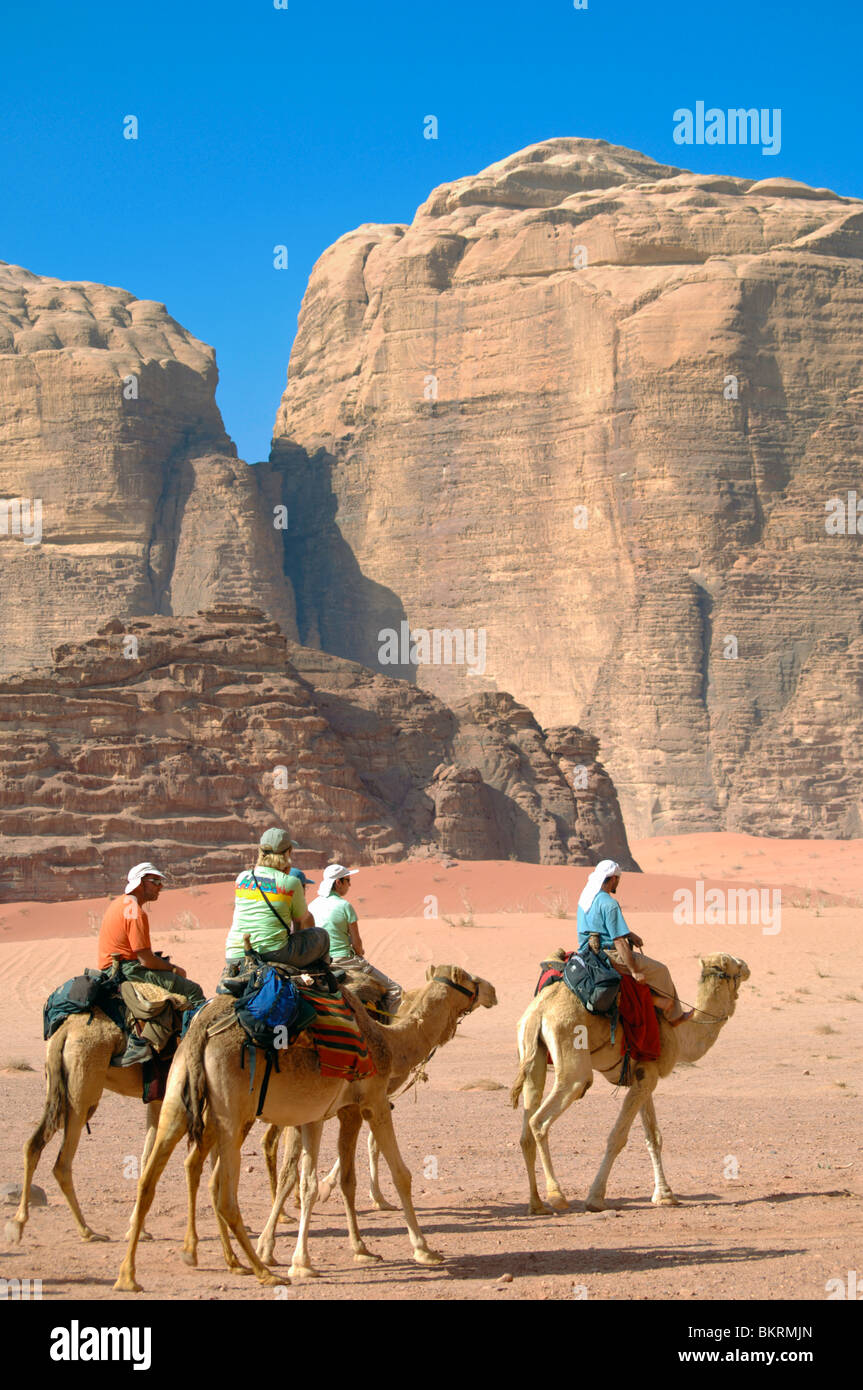Les randonneurs sur les chameaux en dessous des murs de pierre, Wadi Rum, Jordanie Zone protégée Banque D'Images