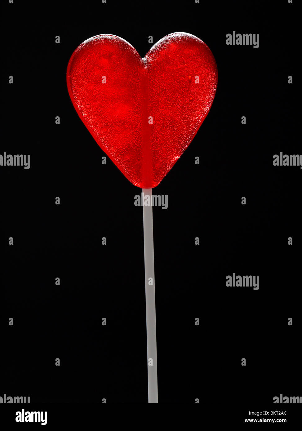 Red Heart-shaped lollipop tourné sur fond noir Banque D'Images