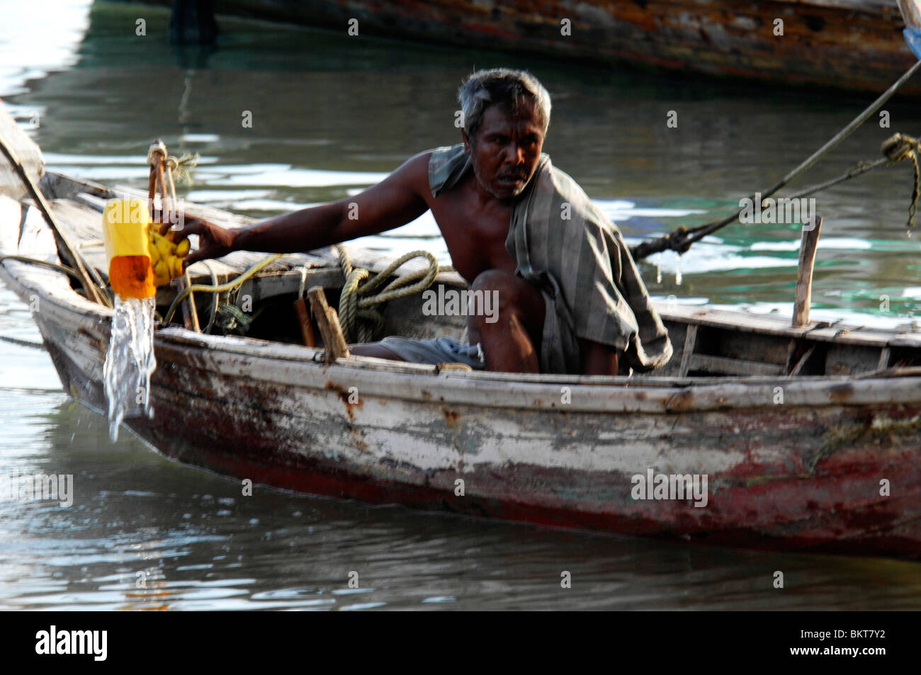 Pêcheur essaie d'obtenir l'eau hors de son navire en perdition , chao leh, sea gypsy village , Rawai Beach , l'île de Phuket, Thaïlande Banque D'Images