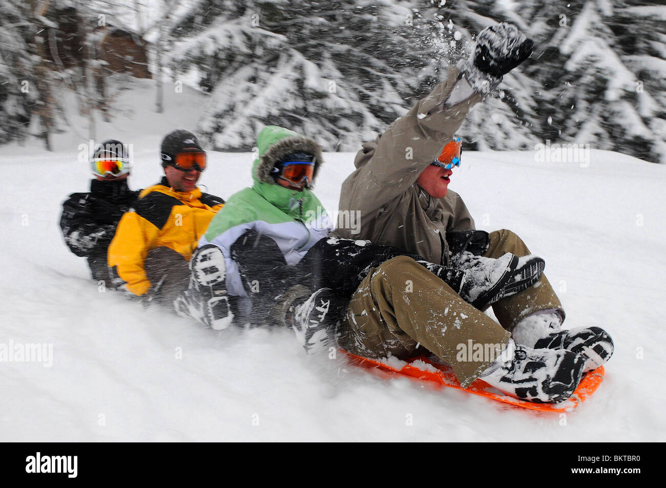 Un groupe d'amis des liens entre faire du traîneau en bas d'une pente dans la station de ski française de Courchevel 1650. Banque D'Images