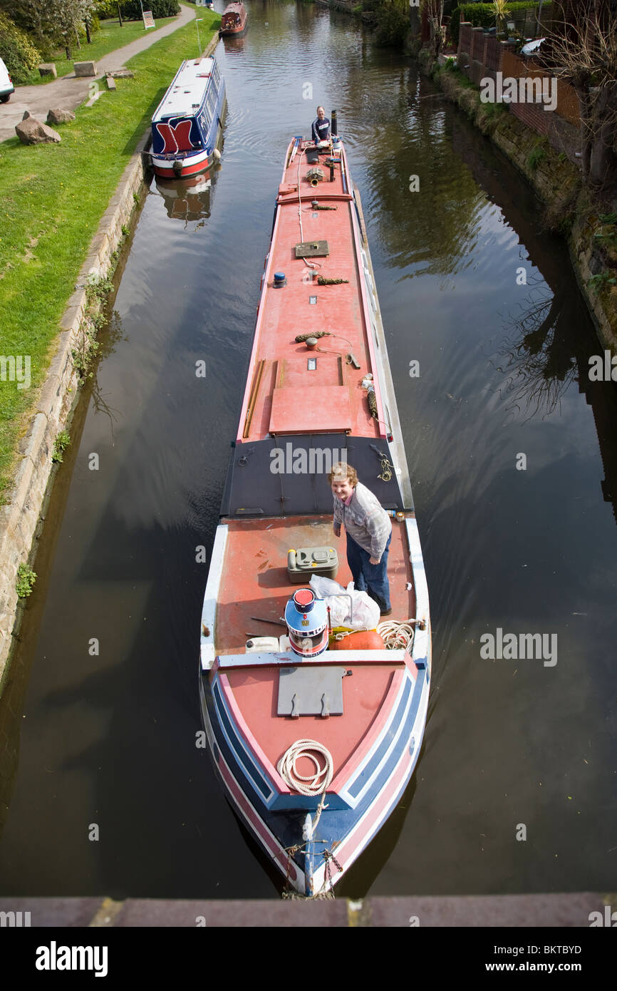 Un étroit canal boat sur le point de passer sous un pont sur le Canal Grand Union, Loughborough, Leicestershire, Angleterre. Banque D'Images