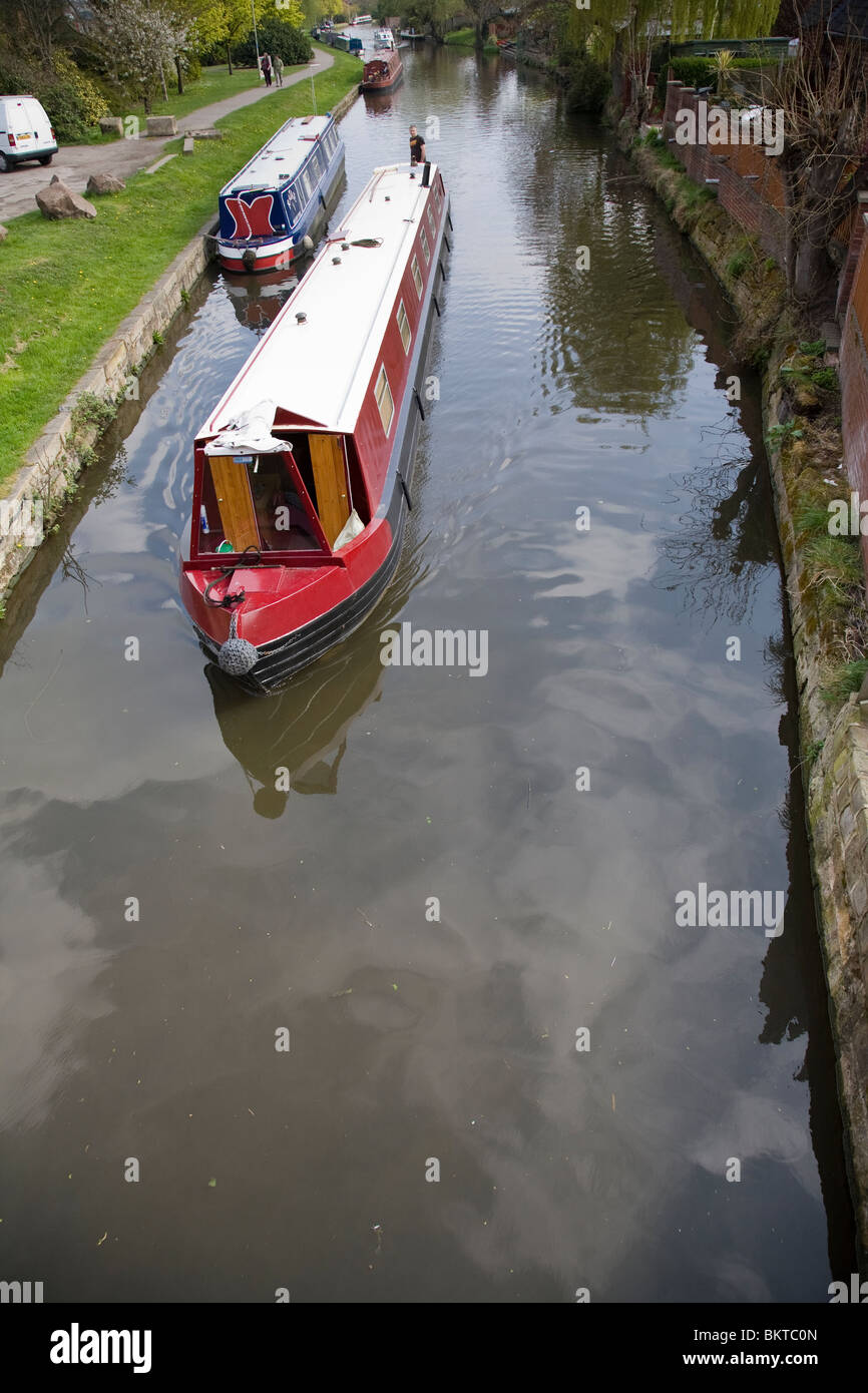 Un homme à la barre d'un bateau étroit canal comme il passe le long du Grand Union Canal, Loughborough, Leicestershire, Angleterre. Banque D'Images