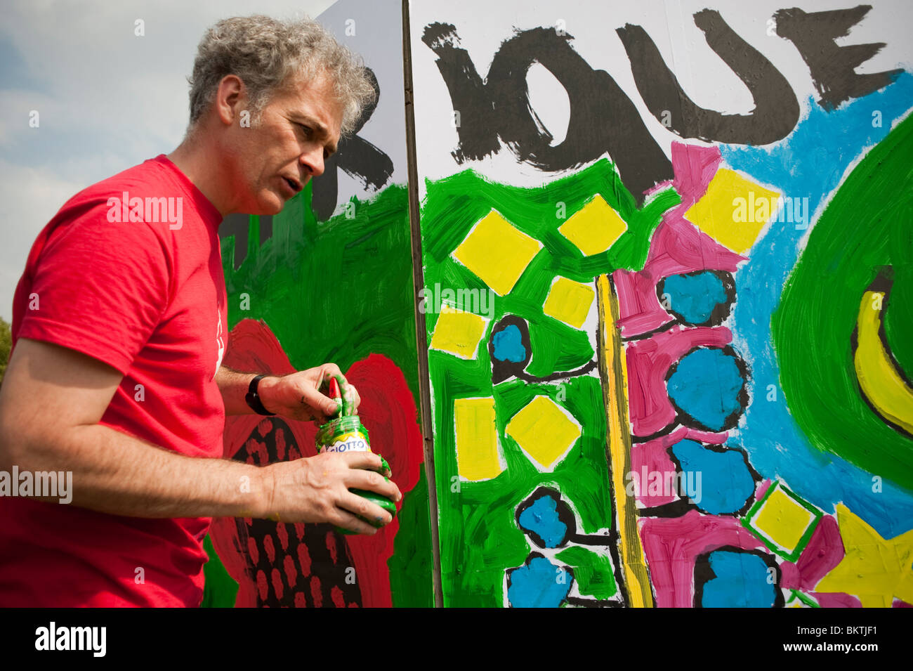 Célébration de la Journée mondiale du commerce équitable, avec un homme peignant une fresque murale dans le parc de la Villette, Art Banque D'Images