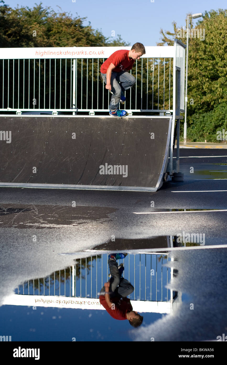 Patinage à roues alignées sur un quarter pipe meuler avec réflexion in puddle Banque D'Images