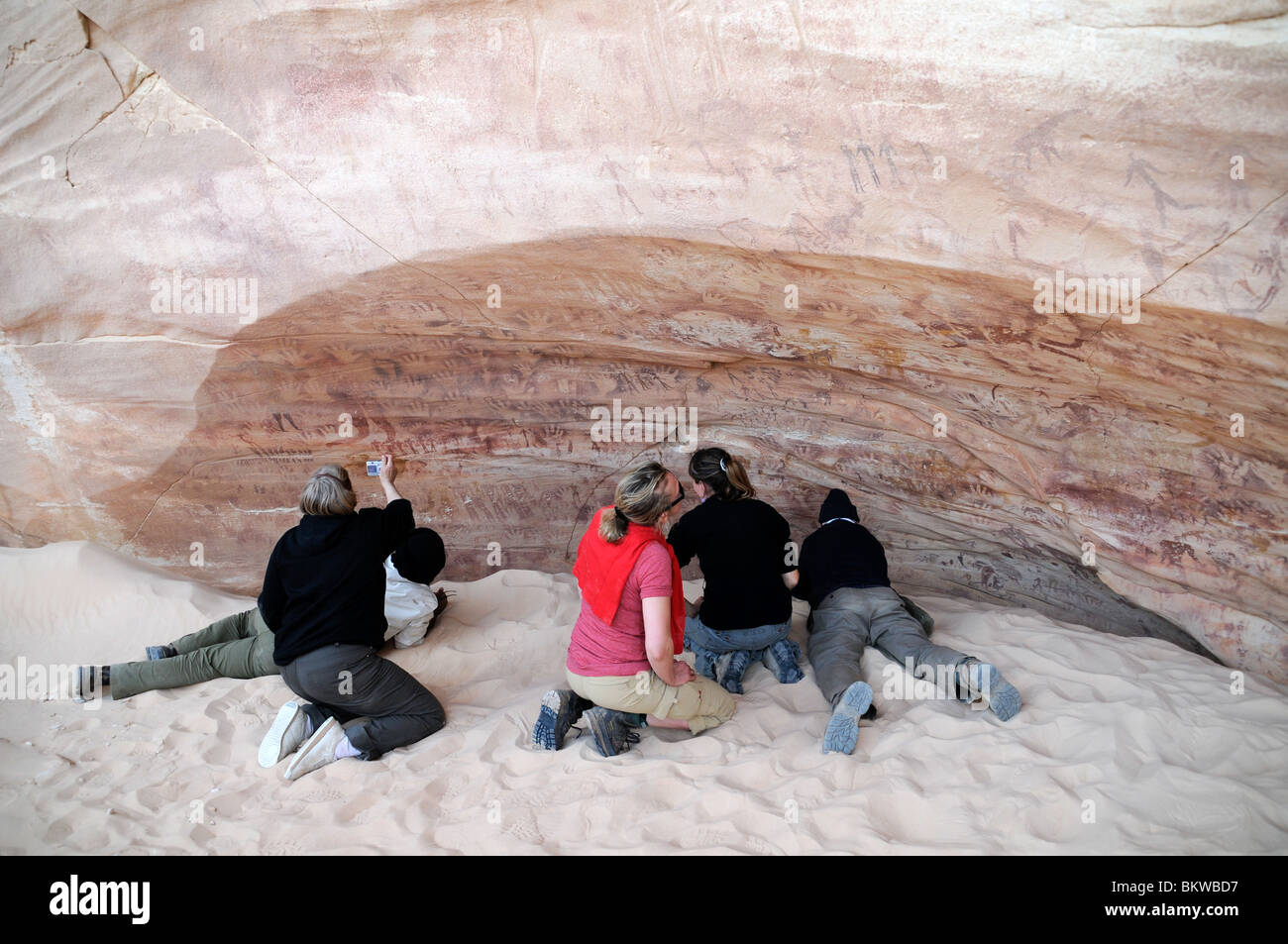 Les voyageurs qui examinent l'art rupestre néolithique à la grotte Foggini-Mestikawi, à Wadi Sura, dans la région de Gilf Kebir, dans le désert du Sahara (occidental) en Égypte. Banque D'Images