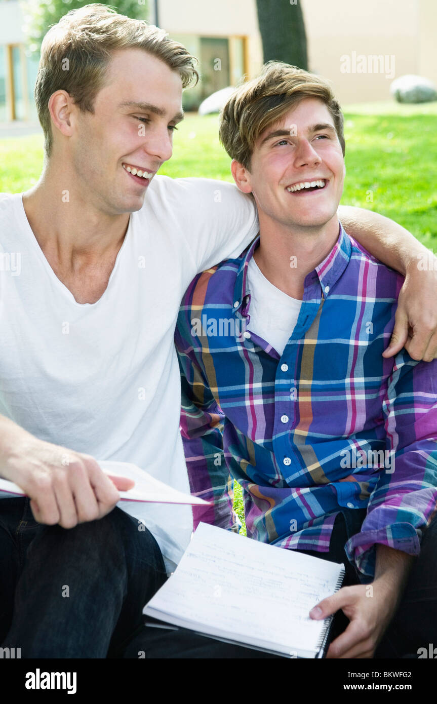 Deux mecs assis dehors sur l'herbe Banque D'Images