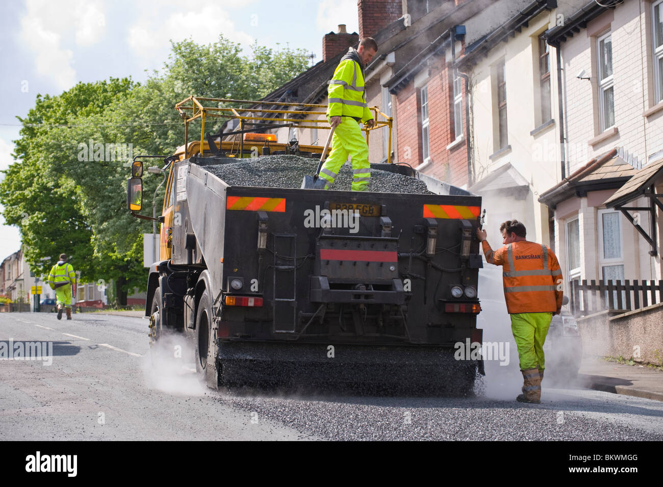 À l'aide d'un resurfaçage des routes de surface de traitement de préservation de l'émulsion de bitume et de gravillons pierre Newport South Wales UK Banque D'Images