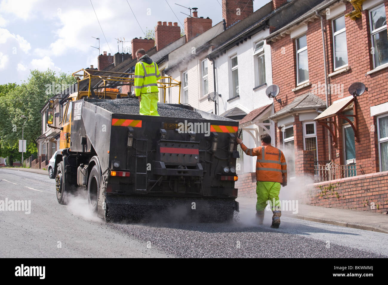 À l'aide d'un resurfaçage des routes de surface de traitement de préservation de l'émulsion de bitume et de gravillons pierre Newport South Wales UK Banque D'Images