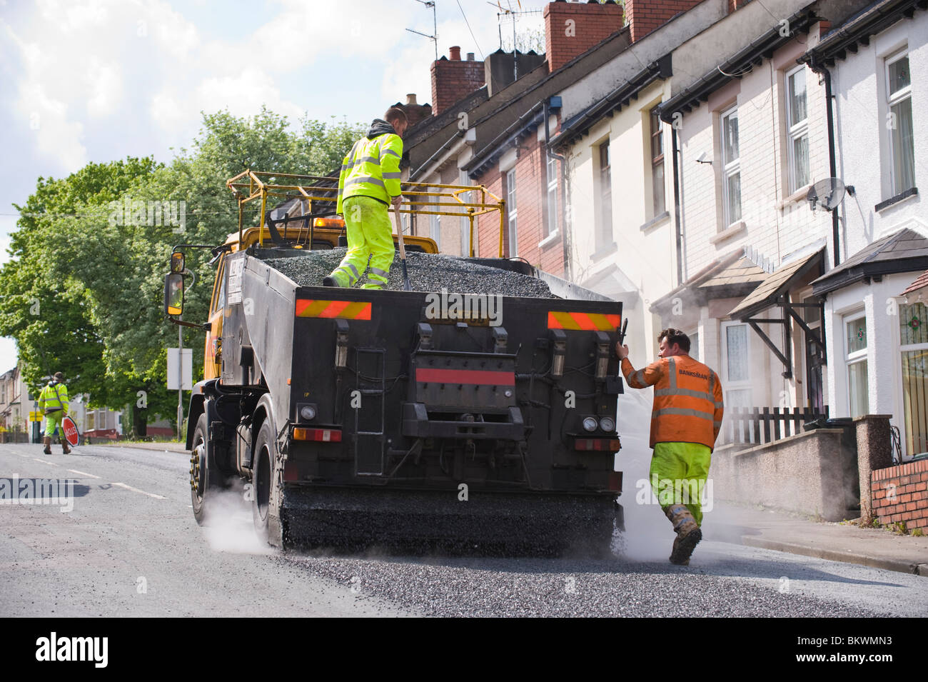 À l'aide d'un resurfaçage des routes de surface de traitement de préservation de l'émulsion de bitume et de gravillons pierre Newport South Wales UK Banque D'Images