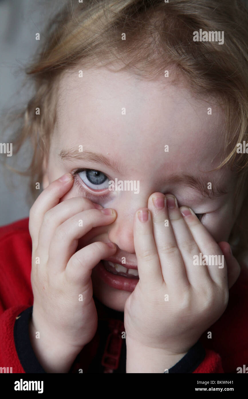 Deux ans enfant bébé fille frotte frotte frotte les yeux fatigués sourire heureux pulling funny face Model publié Banque D'Images