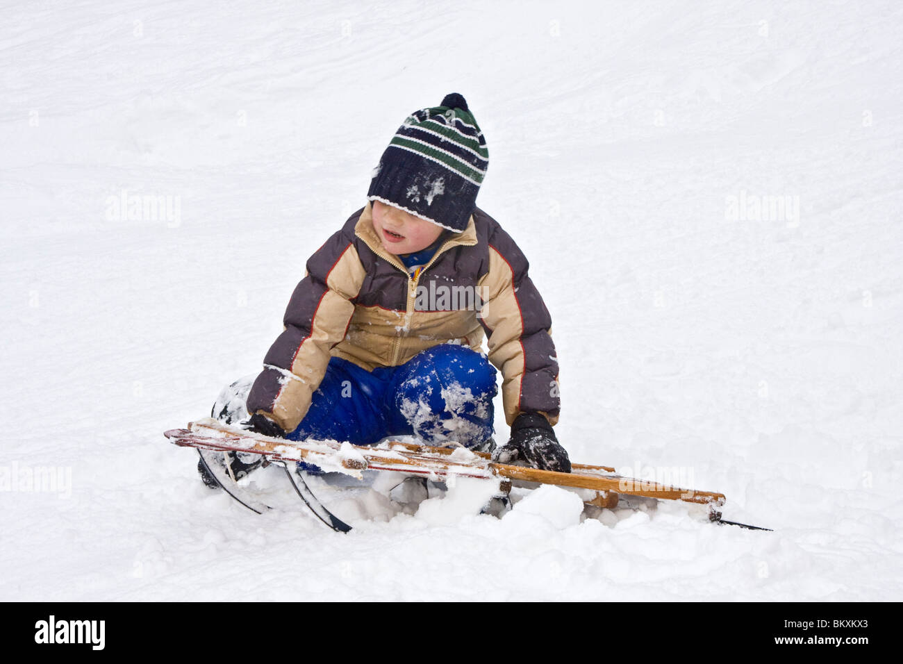 Les enfants en bas de pente courte de traîneau en hiver, South Lake Tahoe, California, USA. Ici un garçon choisit lui-même après un crash. Banque D'Images