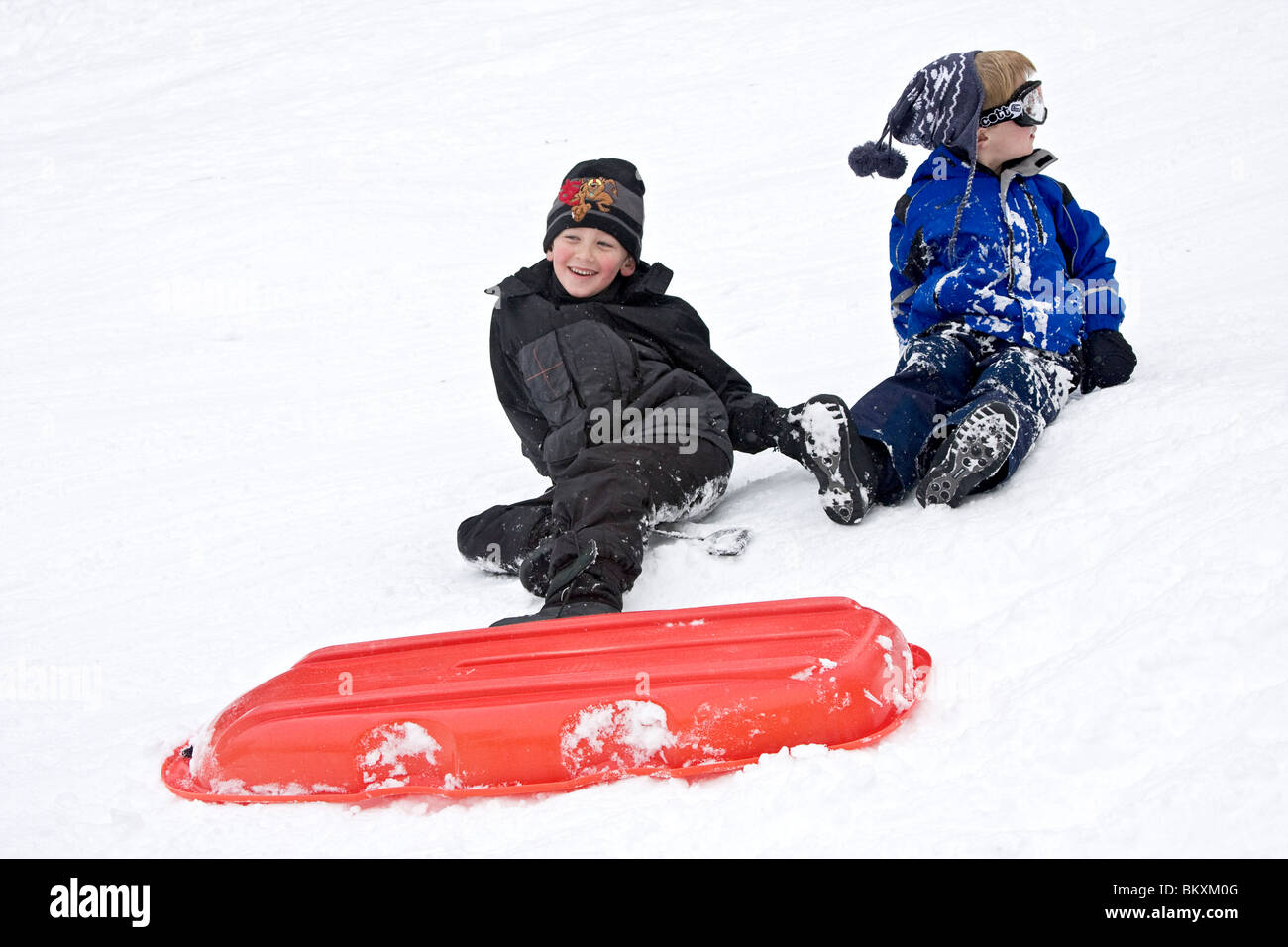 Les enfants en bas de pente courte de traîneau en hiver, South Lake Tahoe, California, USA. Ici deux garçons se démêler après un crash. Banque D'Images