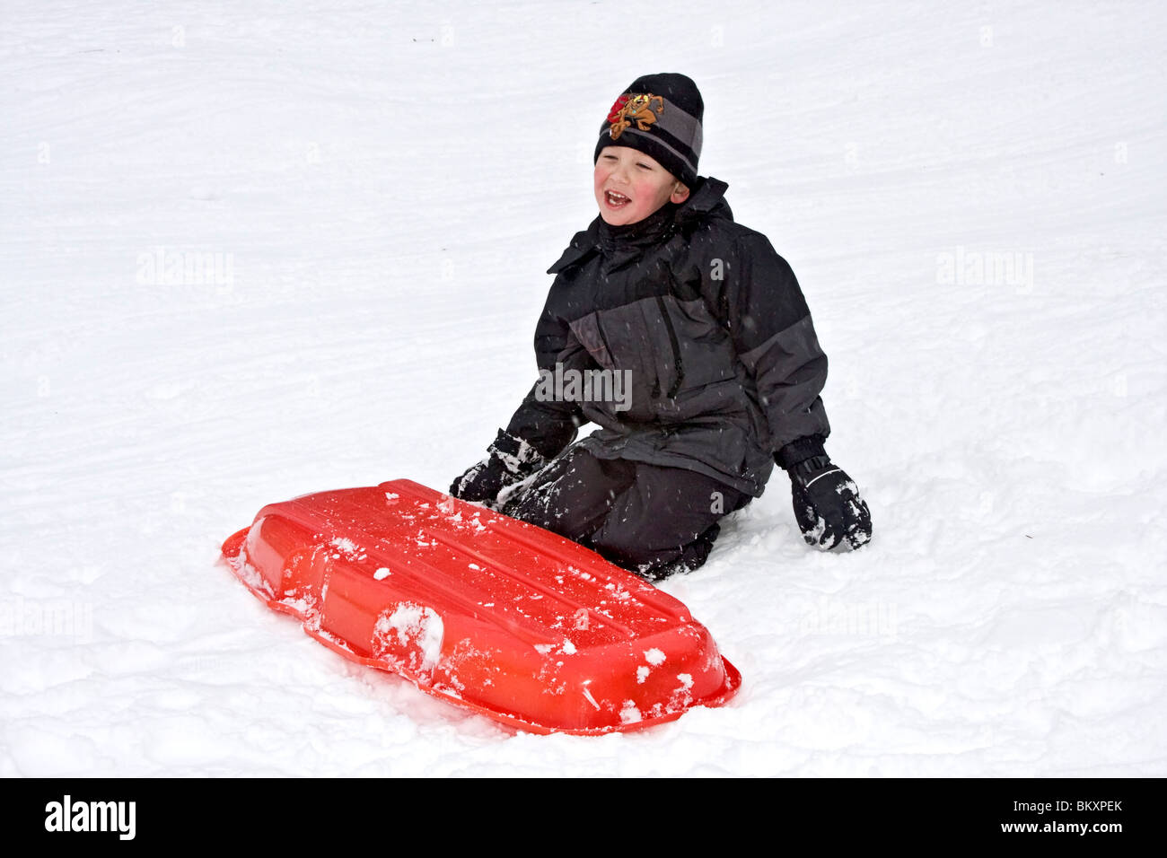 Les enfants en bas de pente courte de traîneau en hiver, South Lake Tahoe, California, USA. Ici un garçon rires après un crash. Banque D'Images