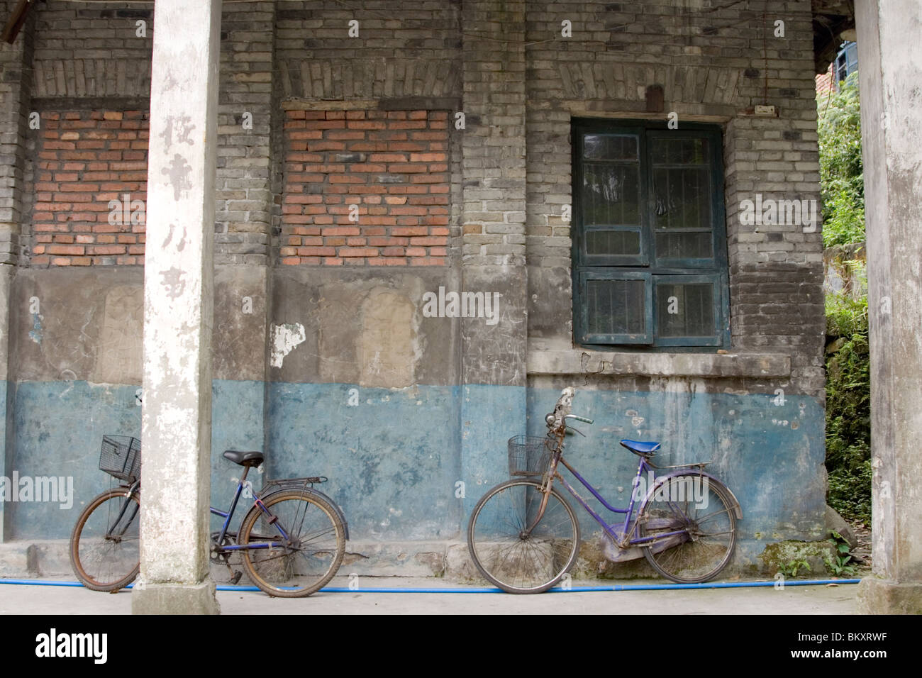 Vieux vélo appuyée sur un vieux mur de brique à la dépendance de l'ancienne mine en ville dans la province du Sichuan en Chine. Banque D'Images