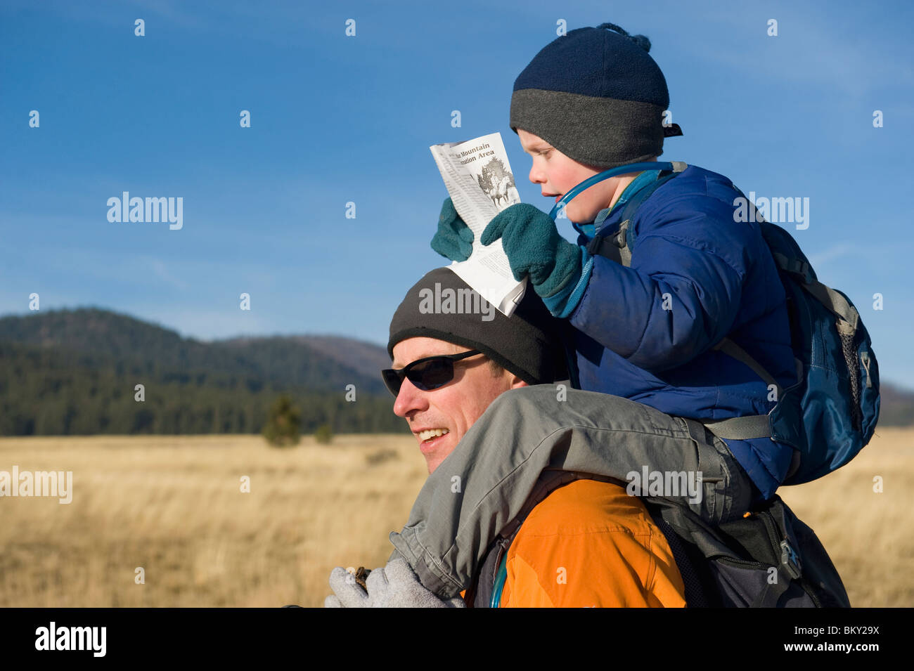 Un jeune garçon prend un tour sur les épaules de son père pendant la lecture d'une carte. Banque D'Images