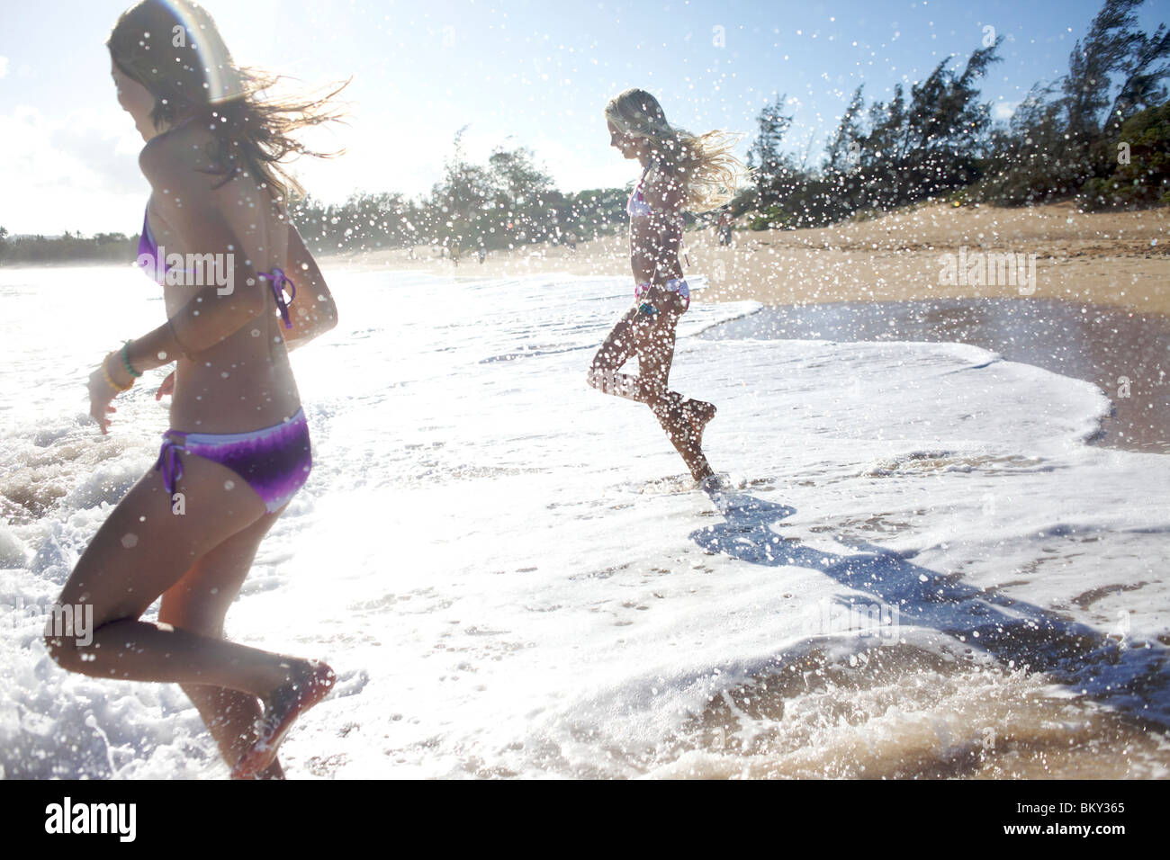 Deux pré-adolescentes fonctionnant à l'eau à la plage de Paia, Maui, Hawaii sourire alors qu'ils sont mouillés. Banque D'Images Deux pré-adolescentes fonctionnant à l'eau à la plage de Paia, Maui, Hawaii sourire alors qu'ils sont mouillés. Banque D'Images
