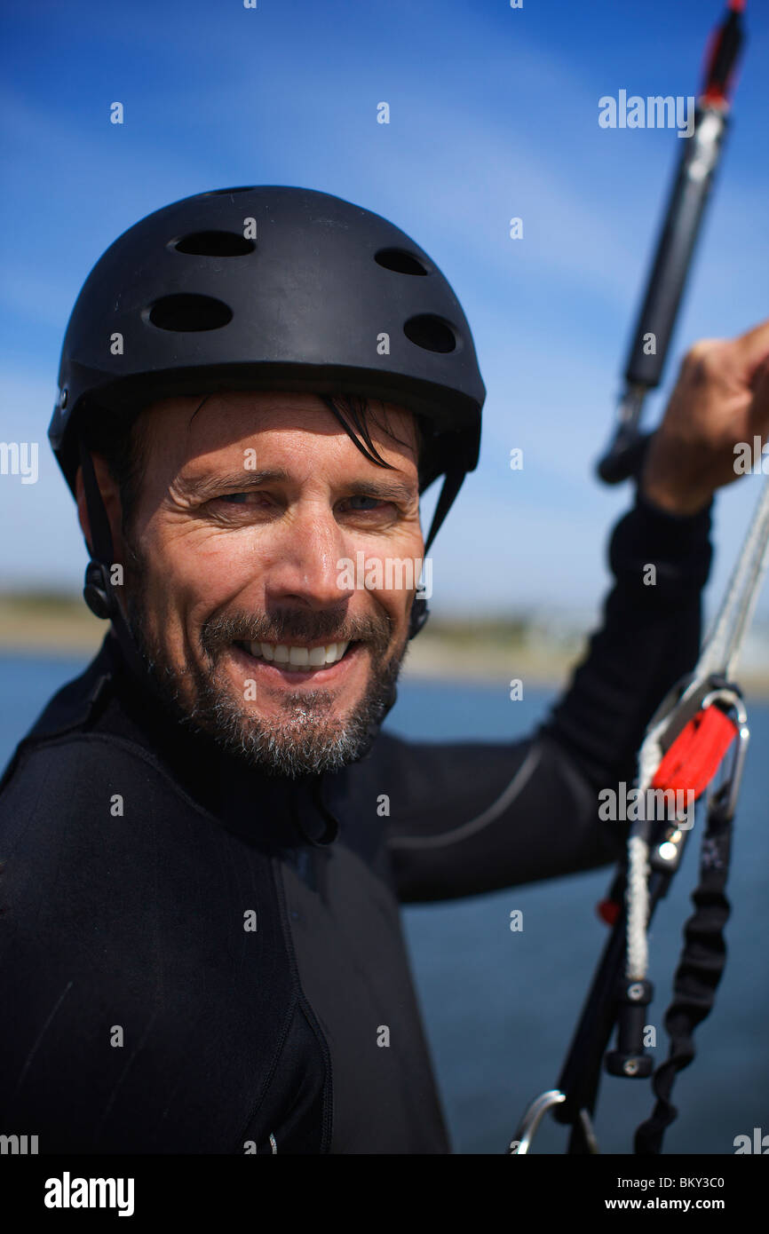 Les hommes autour de 40 ans kitesurfeur ressemble à l'appareil photo tout en maintenant son cerf-volant avec sa main gauche avant d'aller en mission de kitesurf Ba Banque D'Images Les hommes autour de 40 ans kitesurfeur ressemble à l'appareil photo tout en maintenant son cerf-volant avec sa main gauche avant d'aller en mission de kitesurf Ba Banque D'Images