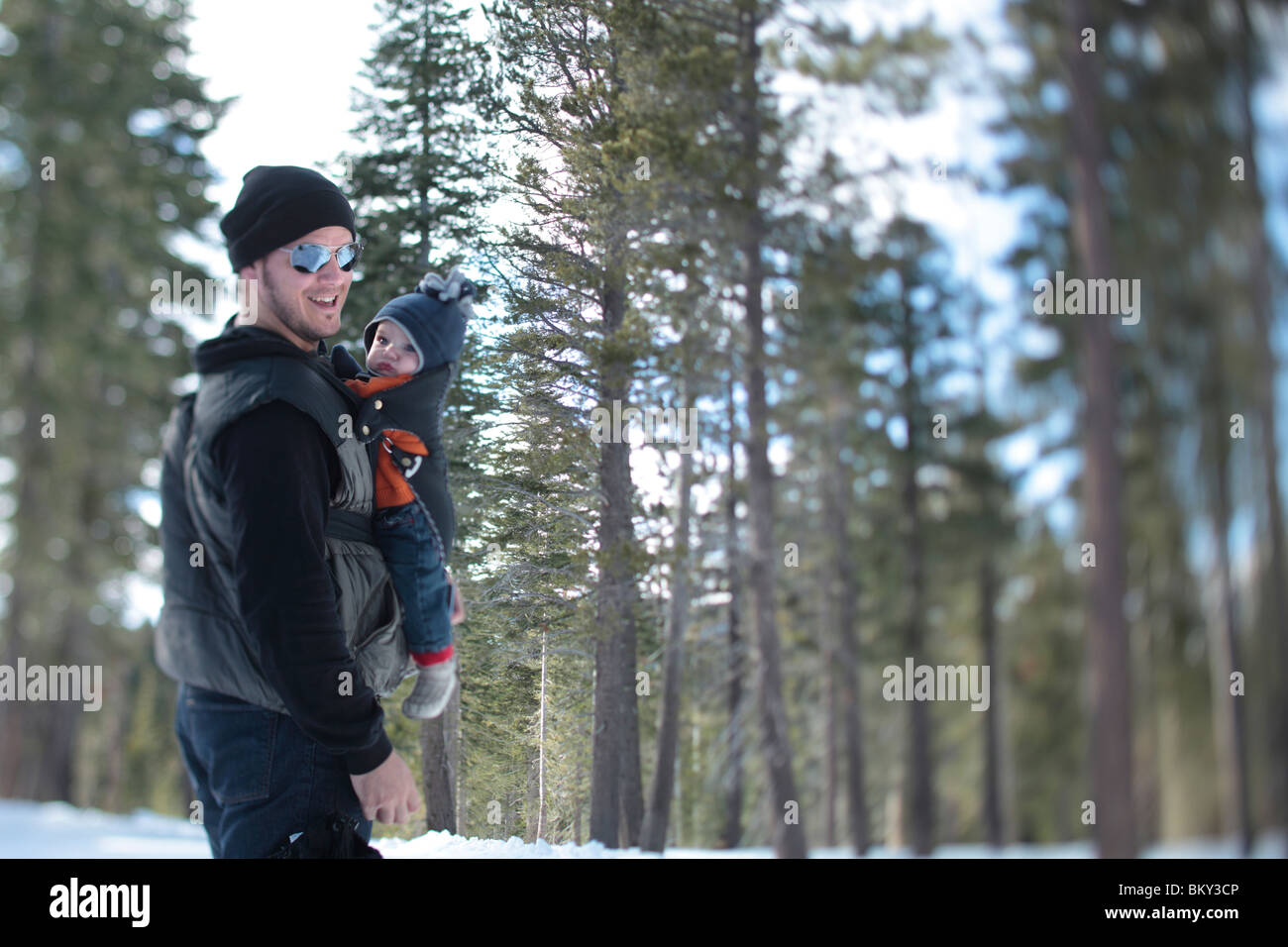 Un père, âgé de 35 ans, marche avec son fils, l'âge de 4 mois, dans le désert couvert de neige du lac Tahoe, Calfornia. Banque D'Images