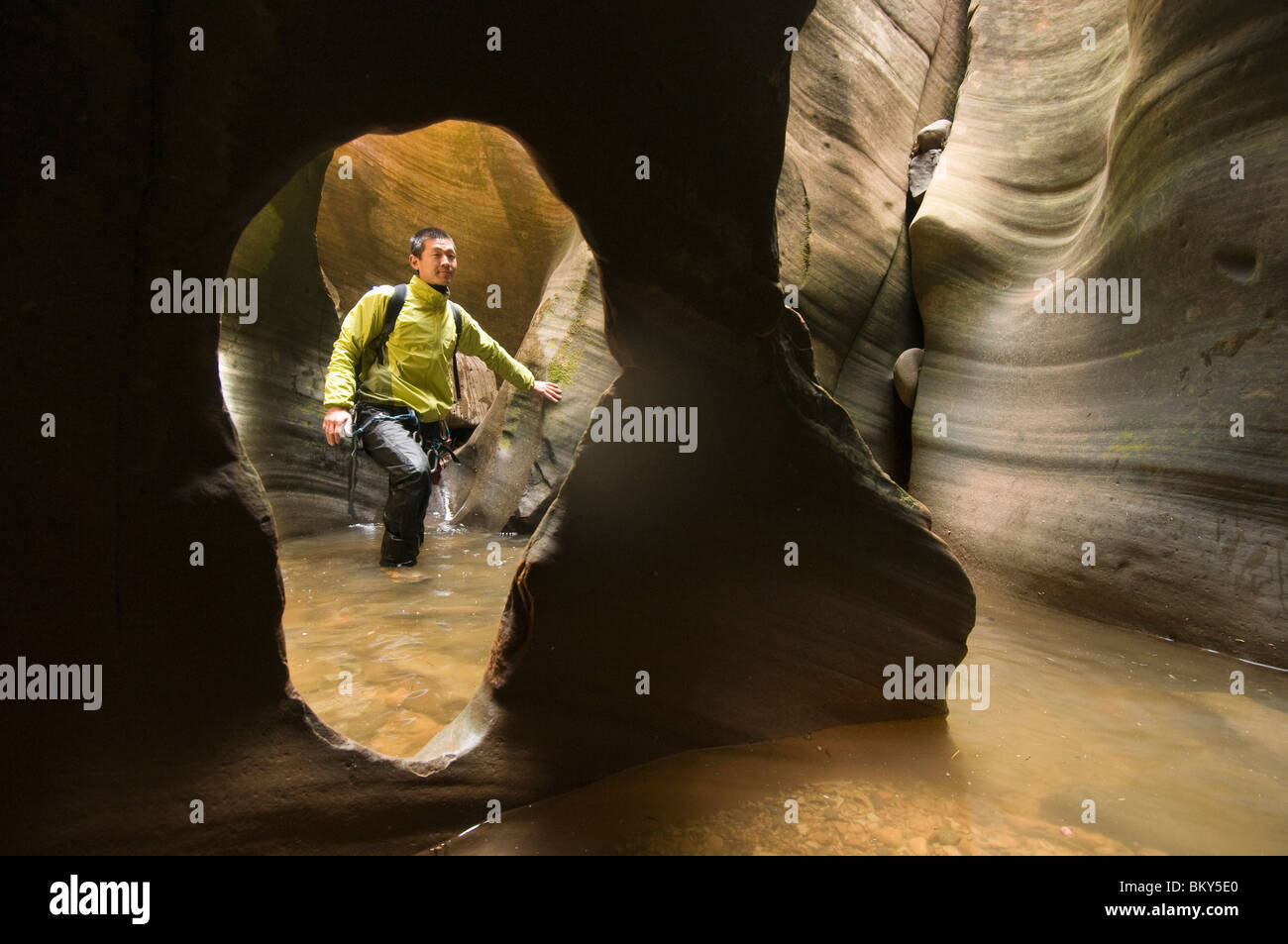 Un homme asiatique le canyoning à travers un canyon aquatique dans la région de Zion National Park, Springdale, Utah. Banque D'Images