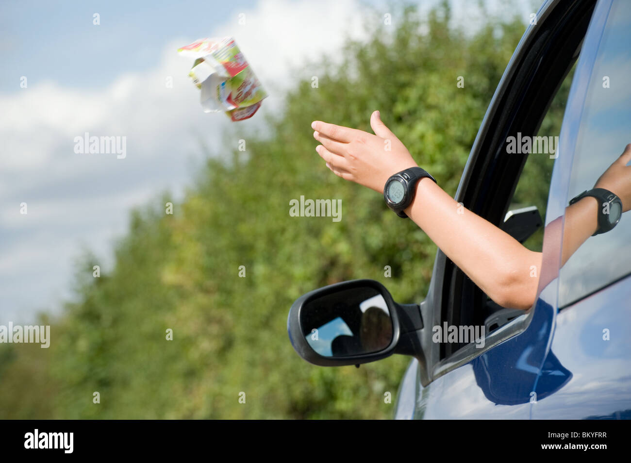 Quelqu'un jeter de déchets hors de la fenêtre d'une voiture. Banque D'Images