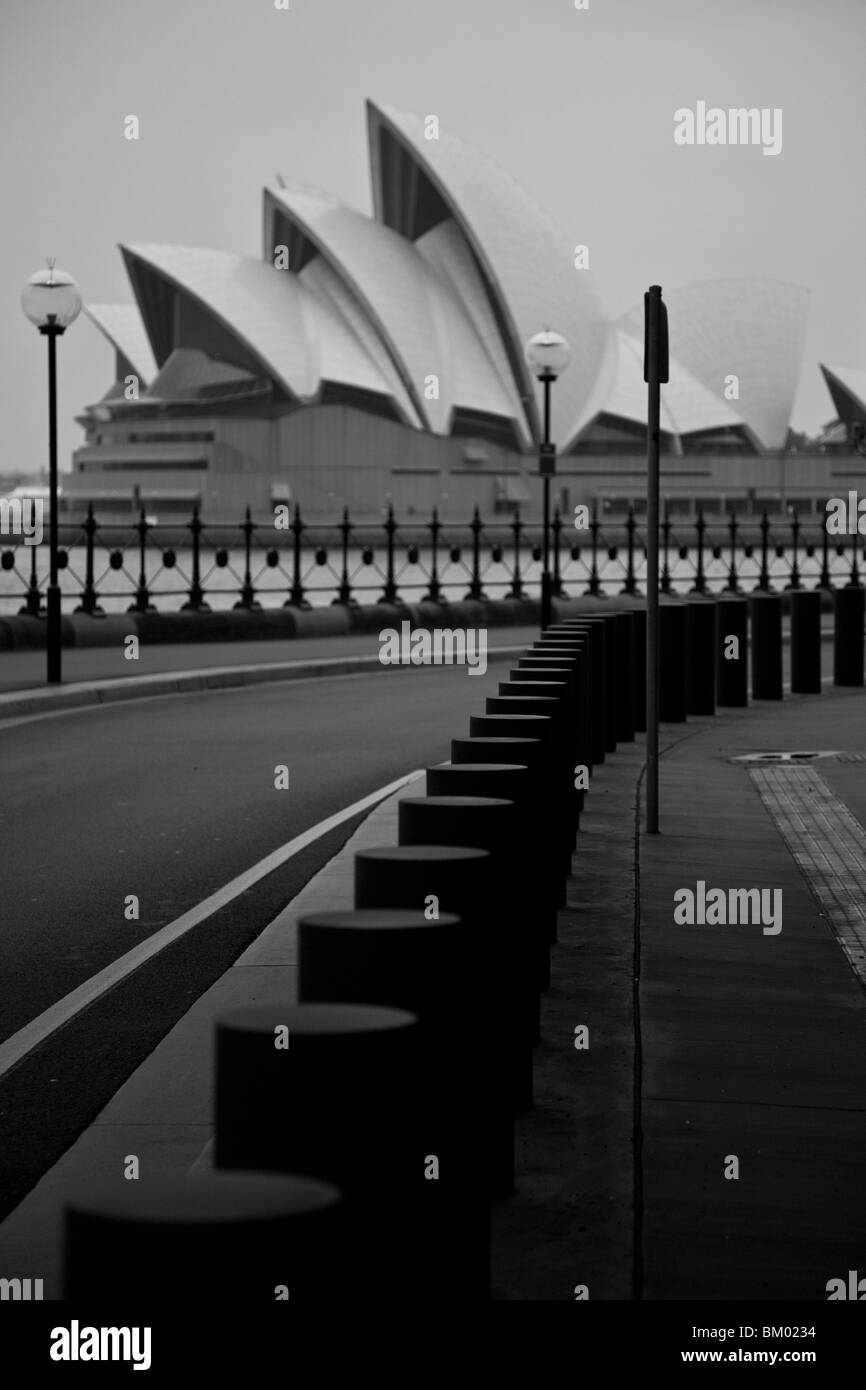 Sydney Opera House à partir de l'autre côté du port, sous le pont, dans une rue avec lampadaires et bornes d'au premier plan Banque D'Images