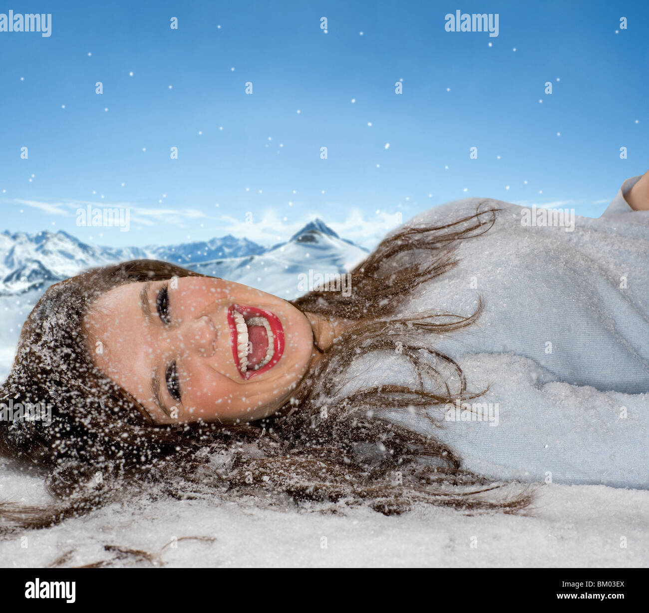 Laughing woman jette dans la neige fraîche Banque D'Images