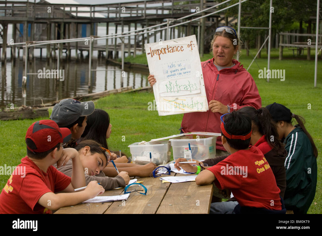Les élèves de collège hispanique prendre des notes pendant que l'instructeur parle de la qualité de l'eau à un centre d'apprentissage en plein air au Texas Banque D'Images