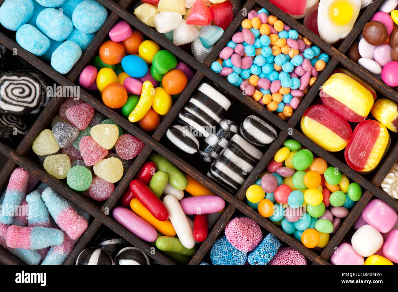 Assortiment de bonbons colorés pour enfants et des bonbons dans un plateau en bois Banque D'Images