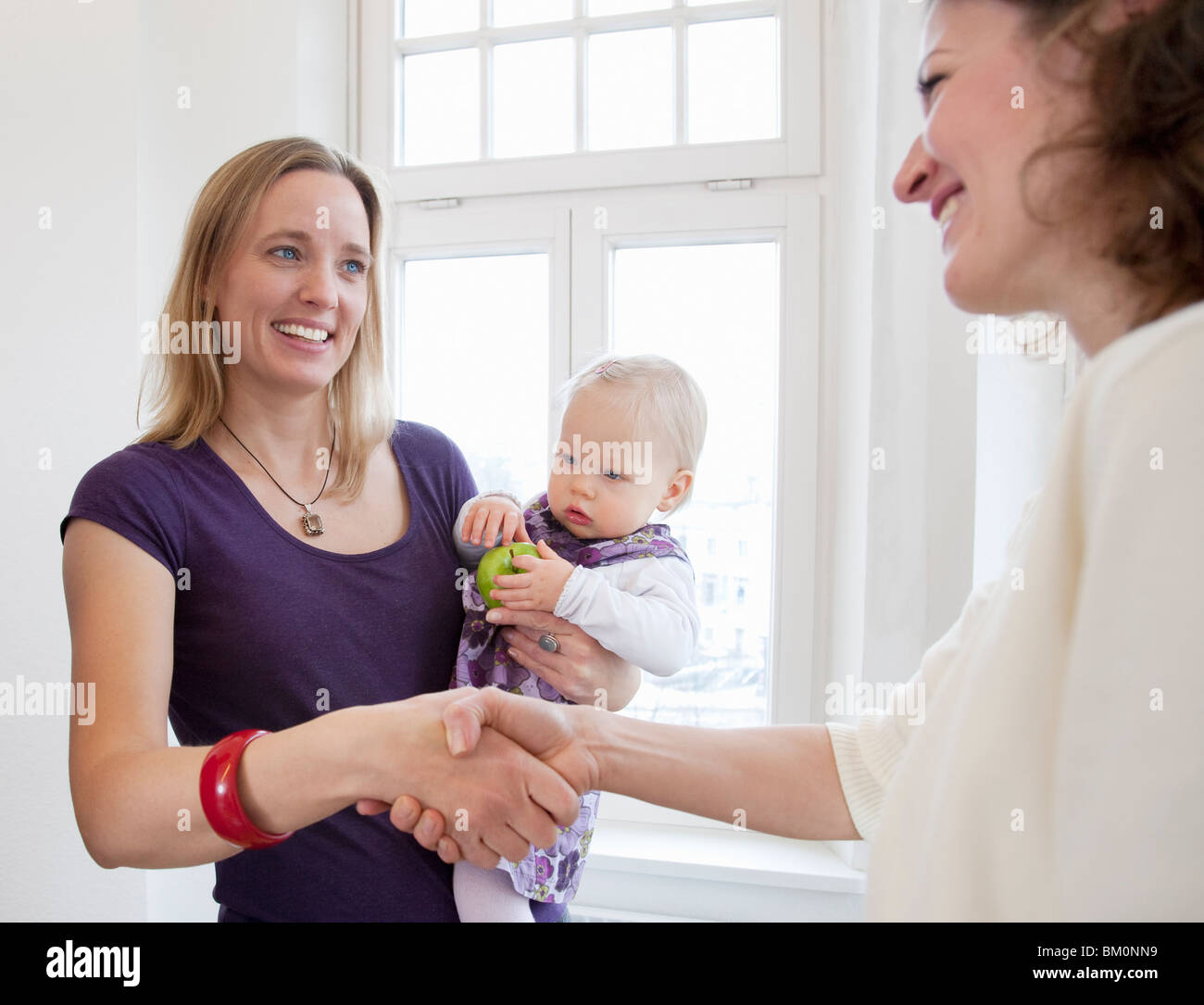 Conseiller femme shaking a mother's hand Banque D'Images