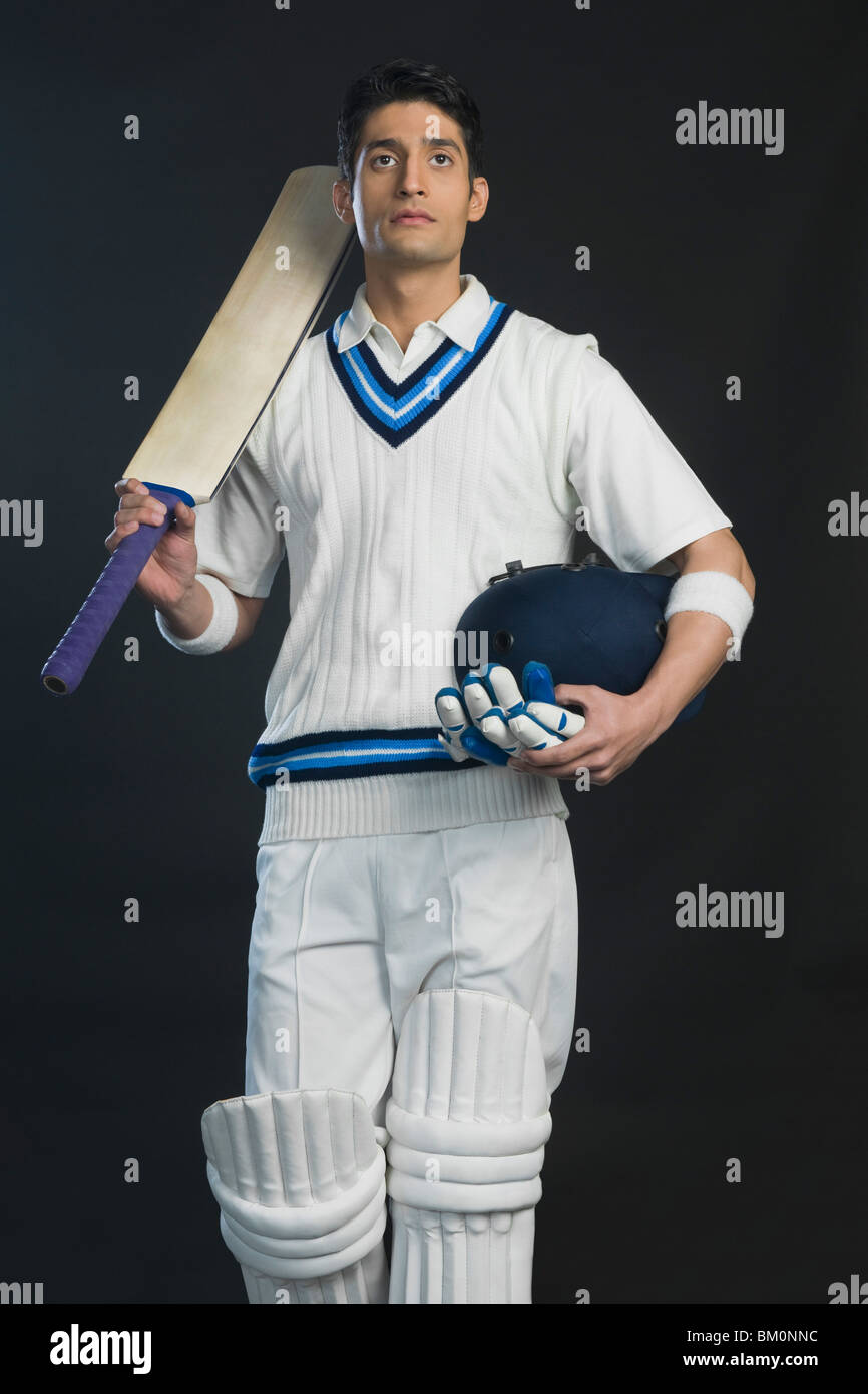 La tenue d'un batteur de Cricket bat avec un casque et des gants Banque D'Images