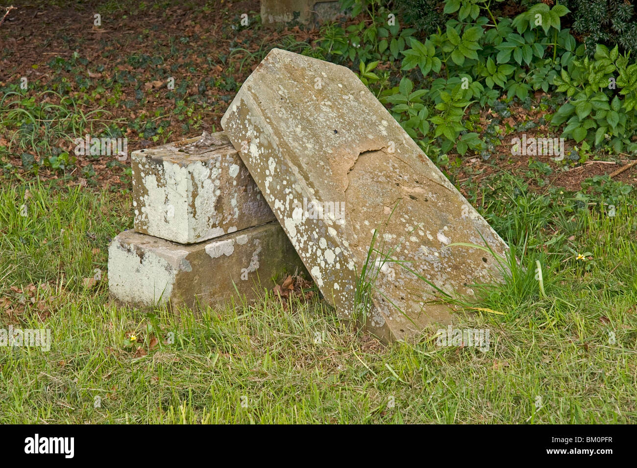 La photo montre une vieille pierre tombale. Le haut est devenu instable et a été retiré de son socle. Banque D'Images