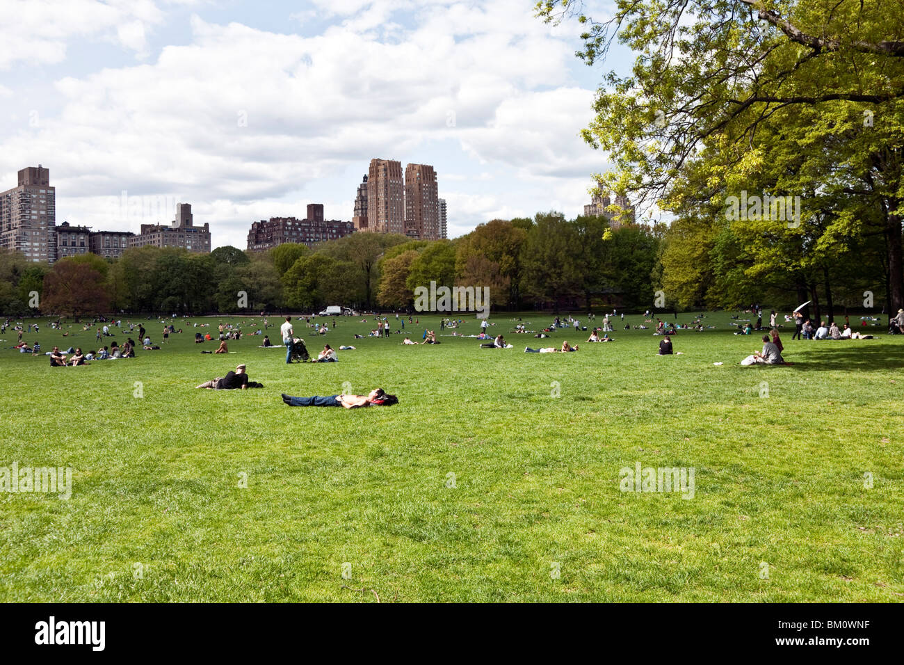 Les gens qui recherchent du soleil & nature parsèment la nouvelle herbe de Central Park Moutons Prairie sous capricieux soleil du printemps New York City Banque D'Images