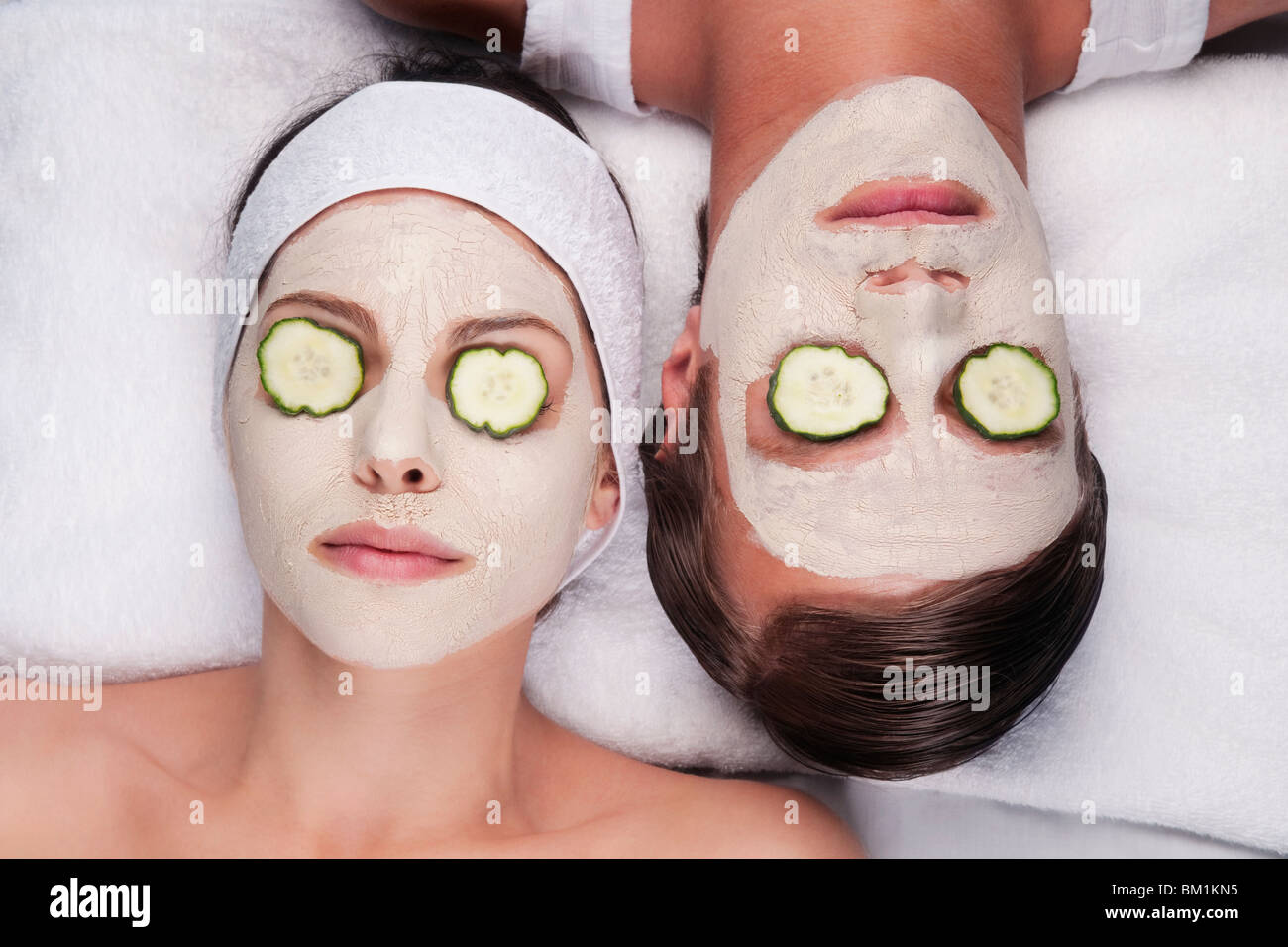 Couple avec masque et tranches de concombre sur les yeux Banque D'Images