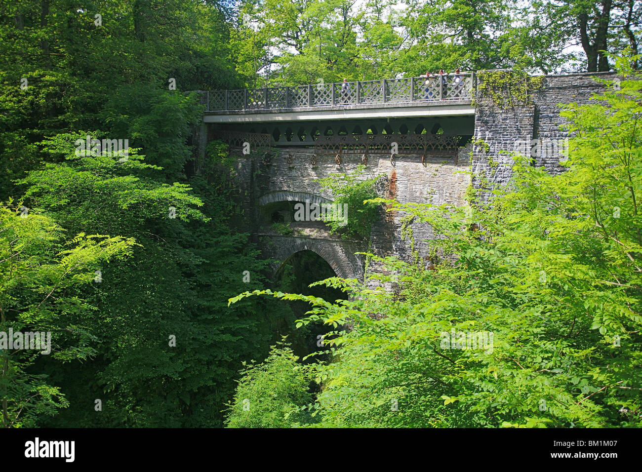 Les touristes à la recherche sur le parapet du trois ponts sur la gorge de la rivière au Pont du Diable, Ceredigion, pays de Galles, Royaume-Uni Banque D'Images