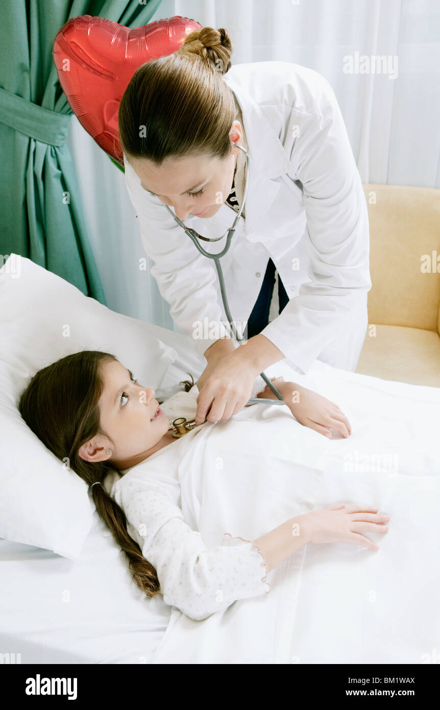Jeune fille sur un lit d'hôpital en cours d'examen par une femme médecin Banque D'Images