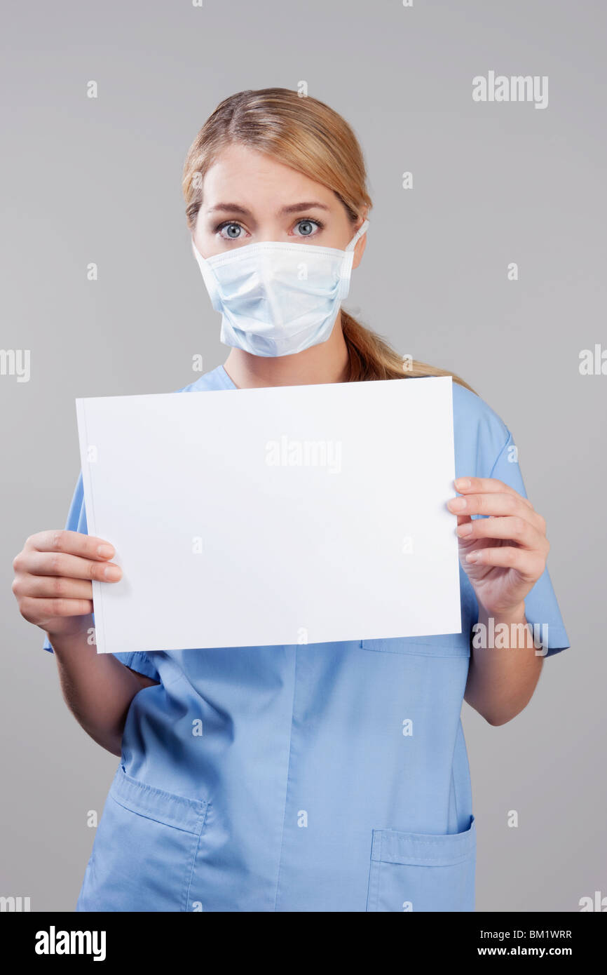 Une infirmière portant un masque de grippe et holding blank placard Banque D'Images