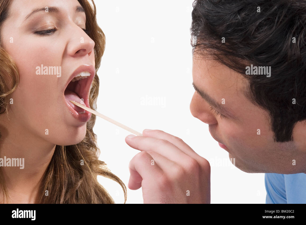 Médecin examinant la gorge d'une femme Banque D'Images