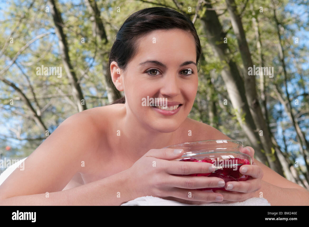 Portrait d'une femme allongée sur une table de massage tenait un bol de pétales de rose Banque D'Images