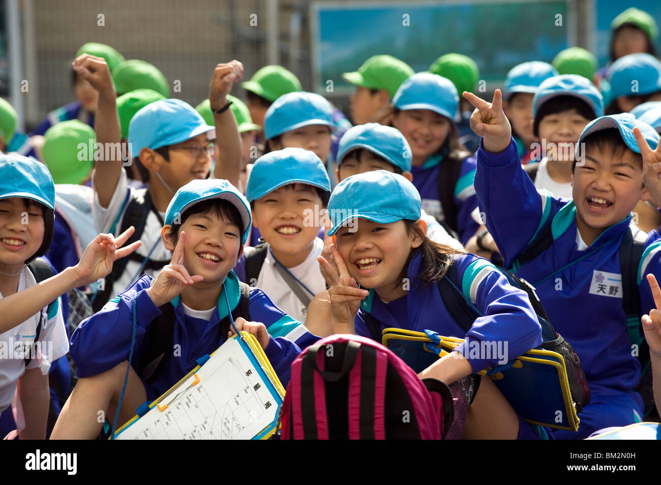 Groupe d'enfants de l'école primaire japonaise souriante portant des chapeaux bleu et vert, Japon Banque D'Images