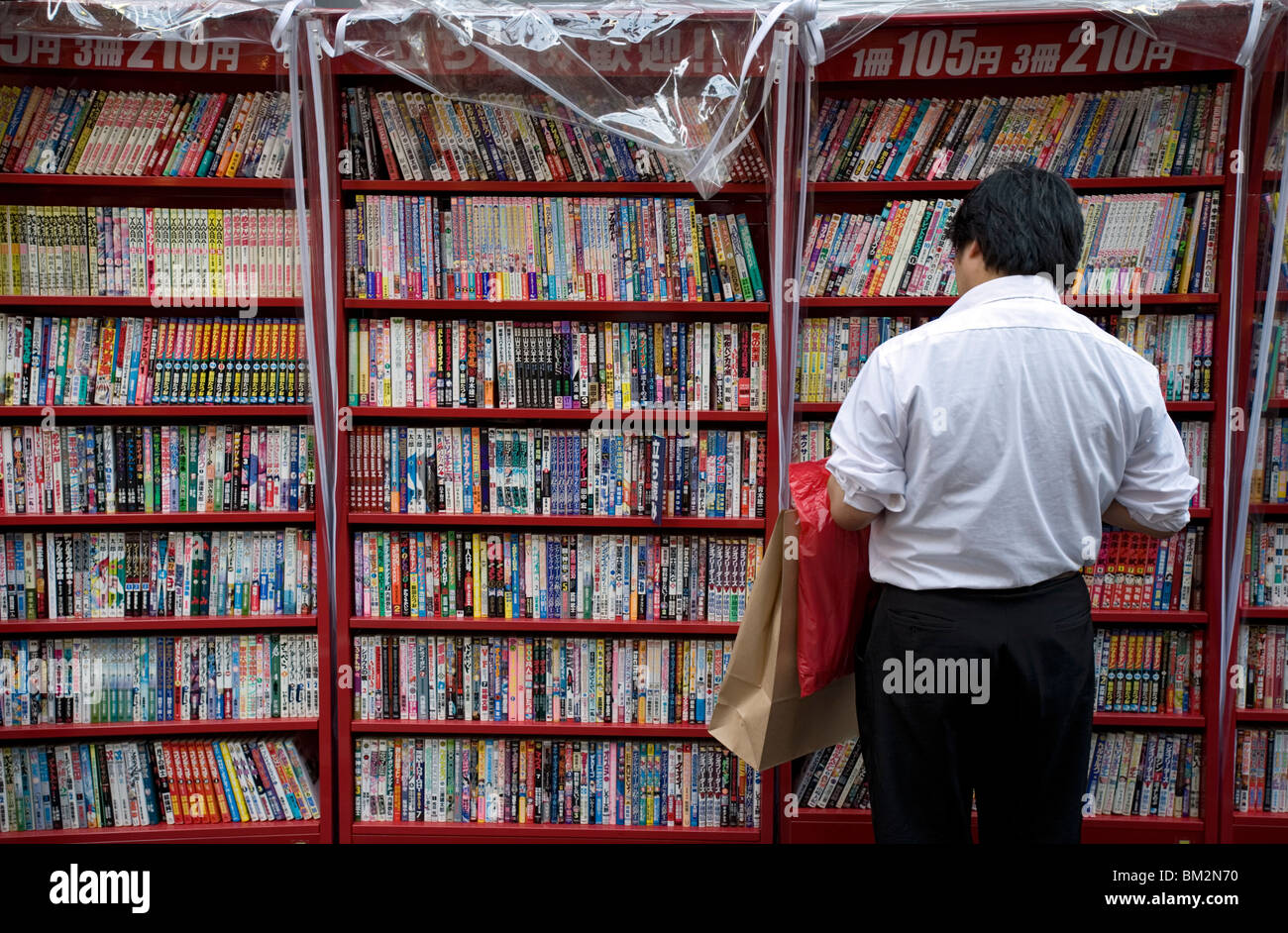 L'homme parcourt les mangas japonais comic books dans un magasin situé à Osaka, Japon Banque D'Images