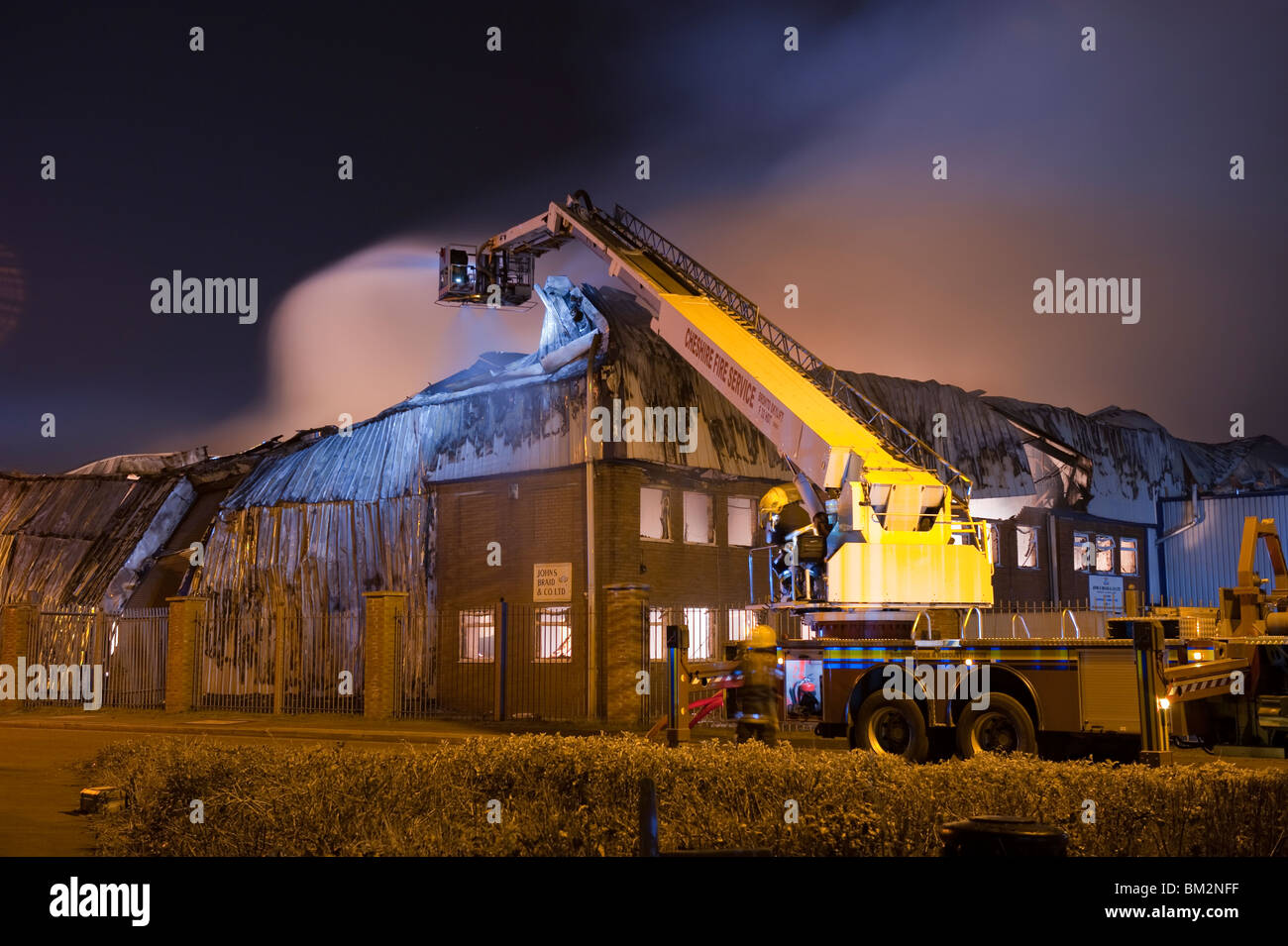 Grande usine-entrepôt en feu la nuit avec beaucoup de flammes et fumée Banque D'Images