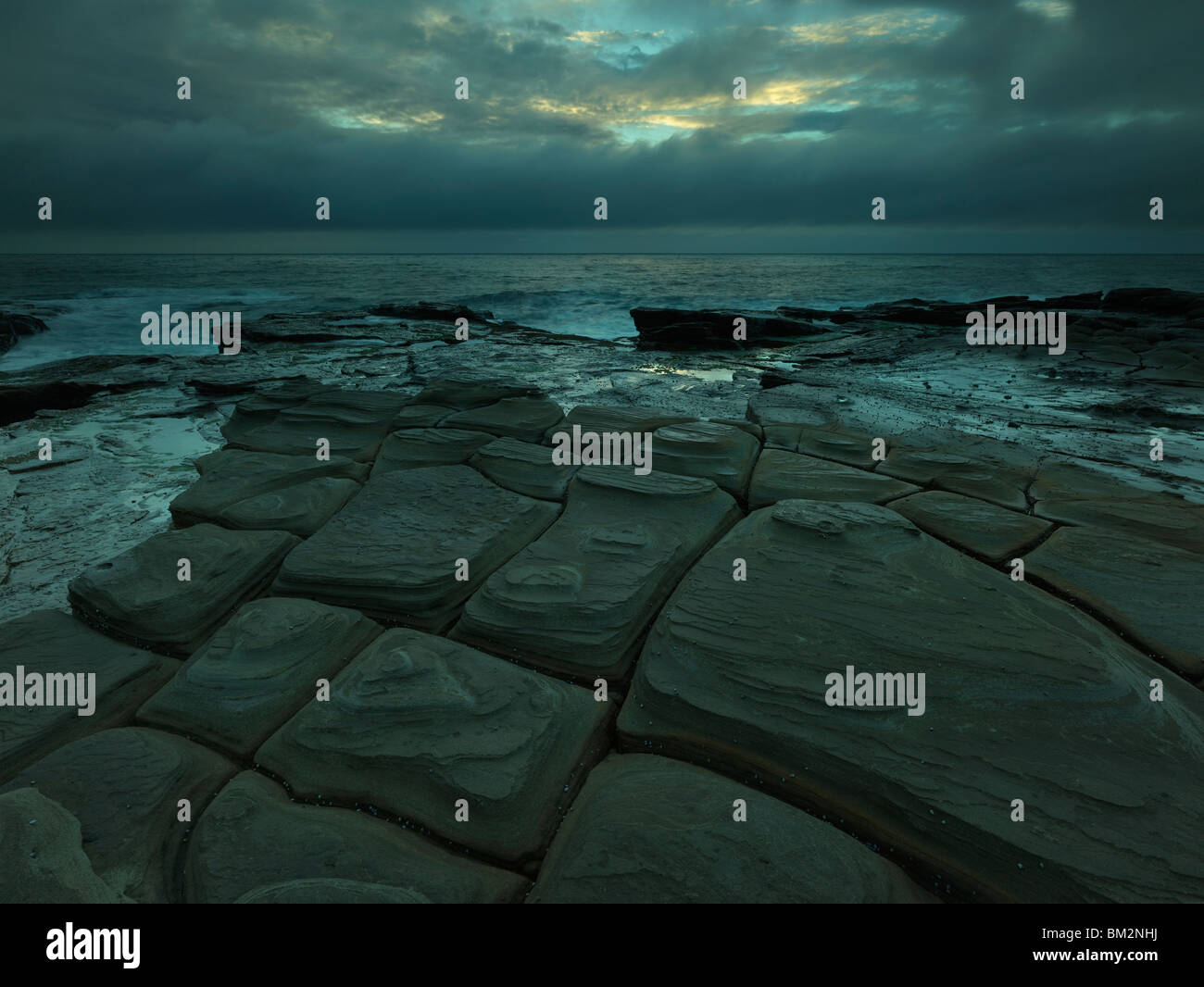Tesselated pavement et lever du soleil sombre. Bouddi National Park, NSW Australie Banque D'Images