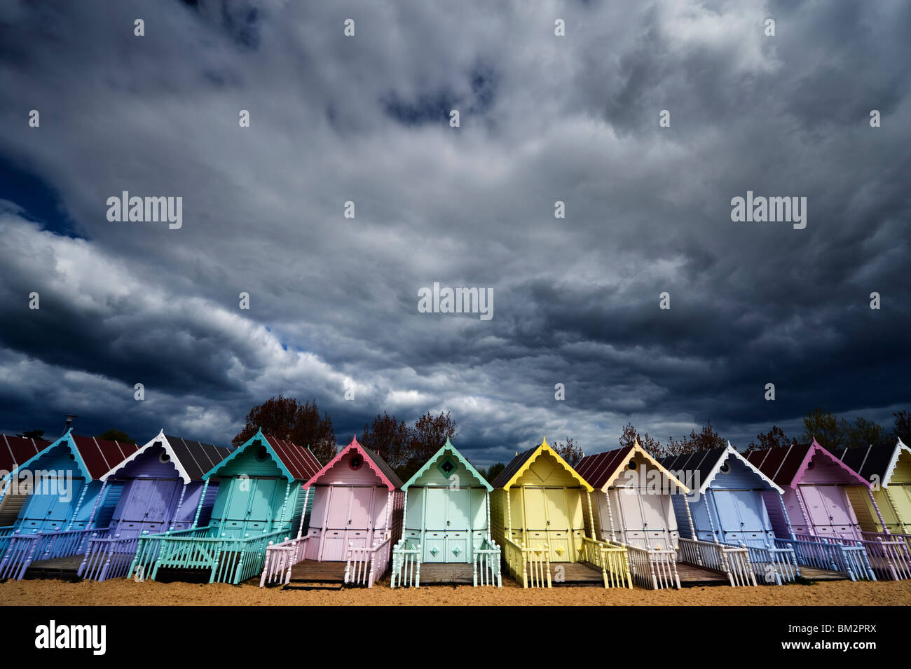 Cabines colorées à la mer contre un ciel nuageux orageux sur l'Est de l'Essex MERSEA Island UK Banque D'Images