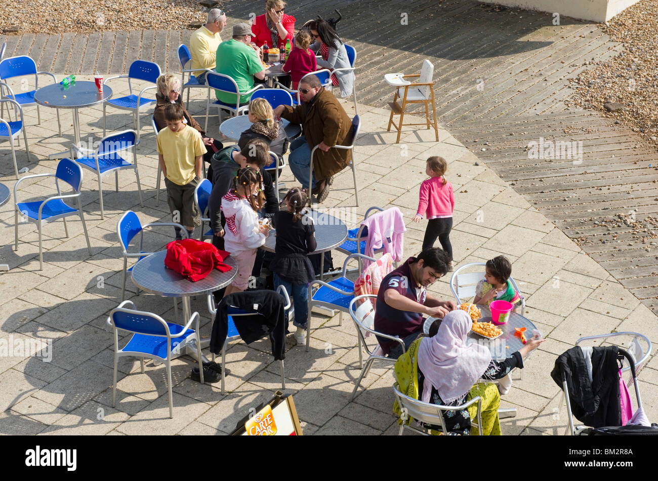 Les gens, les touristes, les excursionnistes assis à des tables et des chaises à la terrasse d'un café avant de Brighton Sussex UK Banque D'Images
