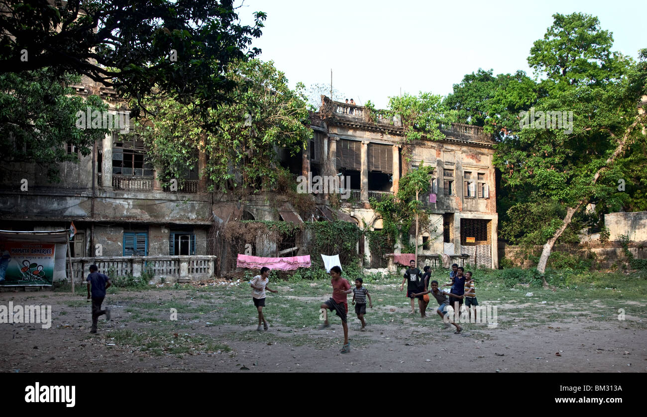 Les enfants jouent en face d'un hôtel particulier délabré Anglais Raj era à Kolkata , Inde, scènes de rue. Banque D'Images