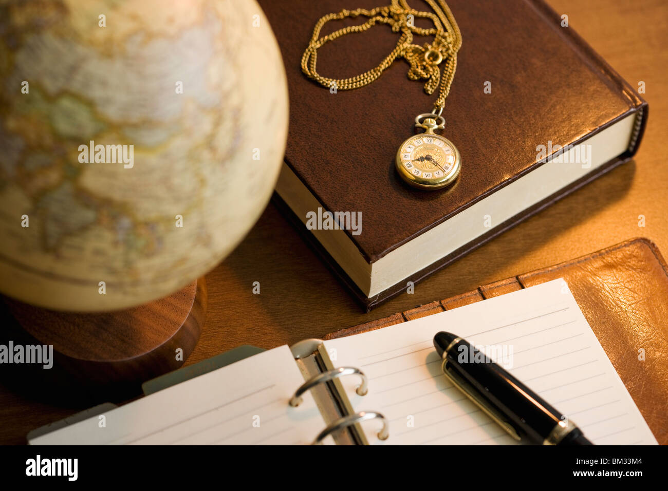 Journal, stylo à encre, livre, et montre de poche sur un bureau Banque D'Images