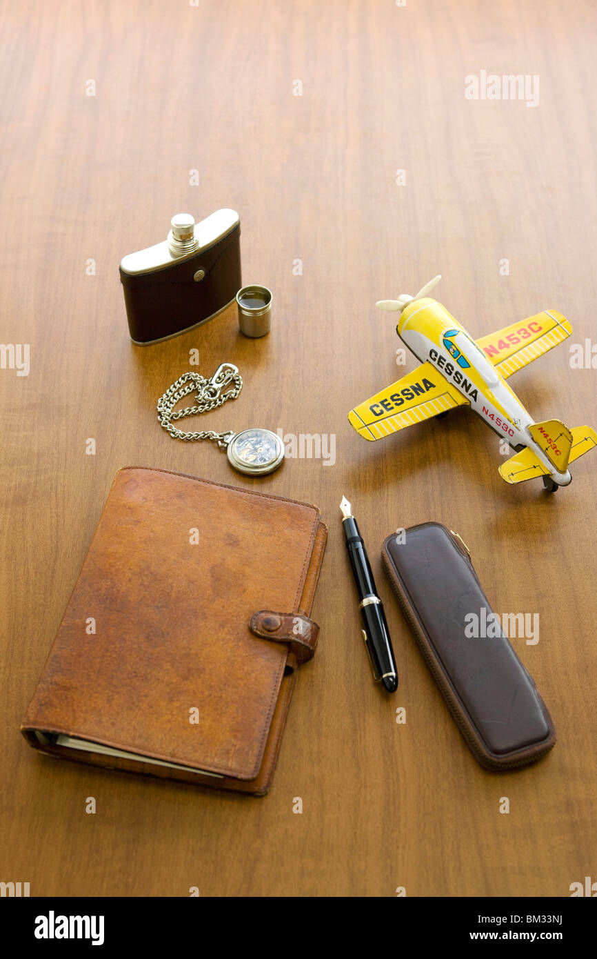 Journal, stylo encre, flacon, montre de poche et model plane sur un bureau Banque D'Images