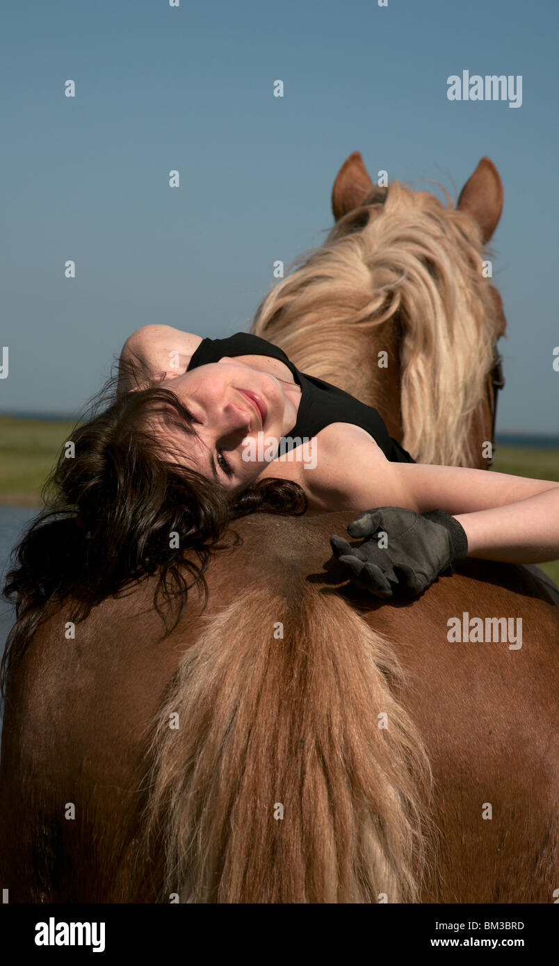 Cavalière sur un cheval brun à pied sur une prairie sauvage Banque D'Images