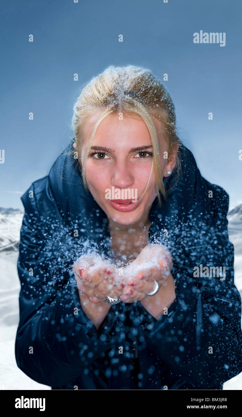 Jeune femme souffle la neige des mains Banque D'Images